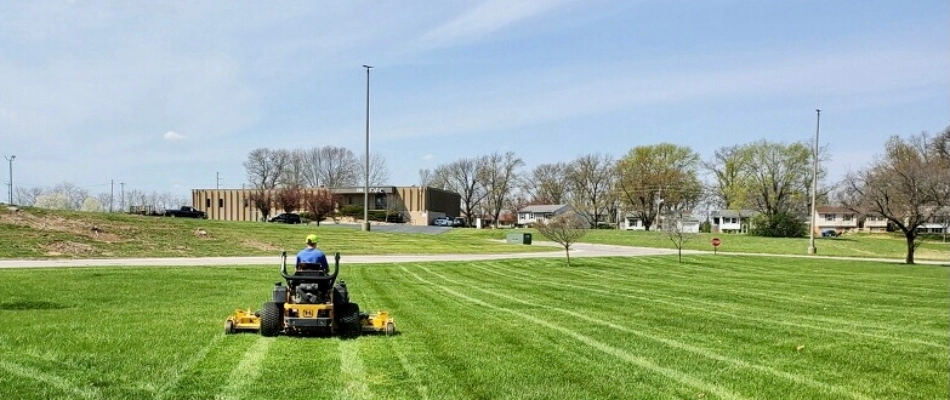 Element professional on riding mower mowing field with stripes added in Brighton, IL.